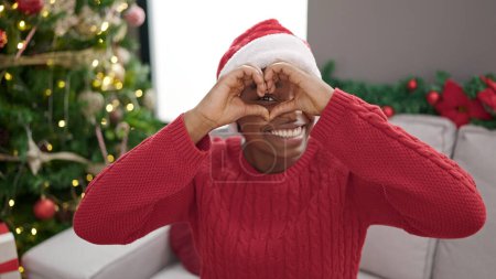 Photo for African american woman celebrating christmas doing heart shape with hands at home - Royalty Free Image