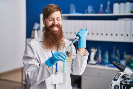 Photo for Young redhead man scientist pouring liquid on test tube at laboratory - Royalty Free Image