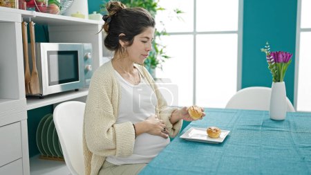 Téléchargez les photos : Jeune femme enceinte prenant le petit déjeuner à la salle à manger - en image libre de droit