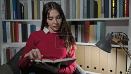 Photo for Young hispanic woman student reading book at library university - Royalty Free Image