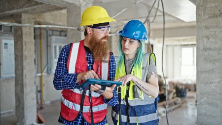 Téléchargez les photos : Constructeurs hommes et femmes utilisant pavé tactile de travail sur le chantier de construction - en image libre de droit