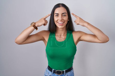 Téléchargez les photos : Young woman standing over isolated background smiling pointing to head with both hands finger, great idea or thought, good memory - en image libre de droit