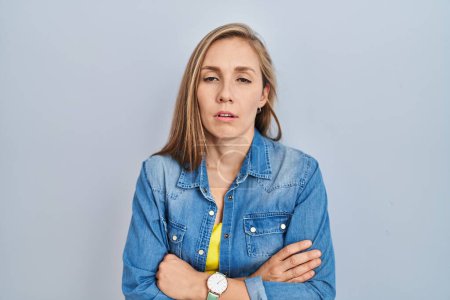 Photo for Young blonde woman standing over blue background looking sleepy and tired, exhausted for fatigue and hangover, lazy eyes in the morning. - Royalty Free Image