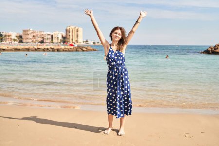 Foto de Joven rubia turista estirando los brazos respirando en la playa - Imagen libre de derechos
