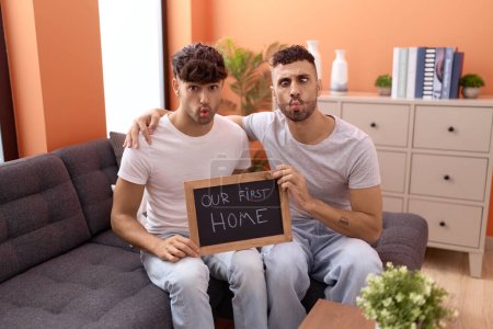 Téléchargez les photos : Homosexuel gay couple tenant tableau noir avec première maison texte faire poisson visage avec bouche et louchant yeux fou et comique. - en image libre de droit