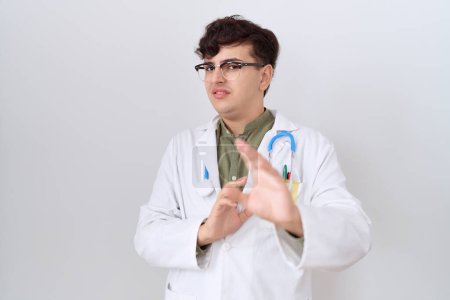 Photo for Young non binary man wearing doctor uniform and stethoscope disgusted expression, displeased and fearful doing disgust face because aversion reaction. with hands raised - Royalty Free Image