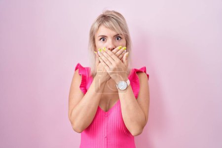 Téléchargez les photos : Jeune femme caucasienne debout sur fond rose choqué couvrant la bouche avec les mains pour erreur. concept secret. - en image libre de droit