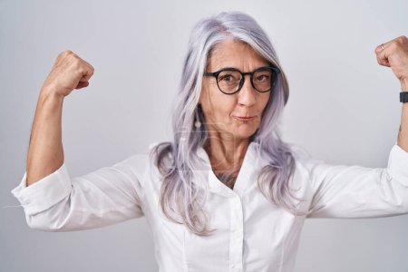 Photo for Middle age woman with tattoos wearing glasses standing over white background showing arms muscles smiling proud. fitness concept. - Royalty Free Image