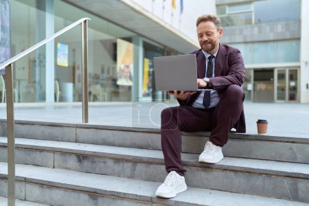 Photo for Middle age man business worker smiling confident using laptop at street - Royalty Free Image