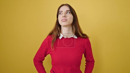 Foto de Mujer hispana joven de pie con expresión seria sobre fondo amarillo aislado - Imagen libre de derechos