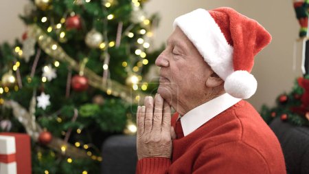Téléchargez les photos : Priant assis près de l'arbre de Noël à la maison - en image libre de droit