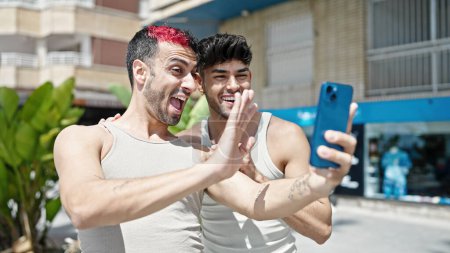 Téléchargez les photos : Deux hommes couple souriant confiant ayant appel vidéo au parc - en image libre de droit