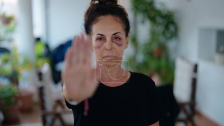 Téléchargez les photos : Femme hispanique du Moyen Age faisant un geste d'arrêt pour violence domestique sur la terrasse de la maison - en image libre de droit