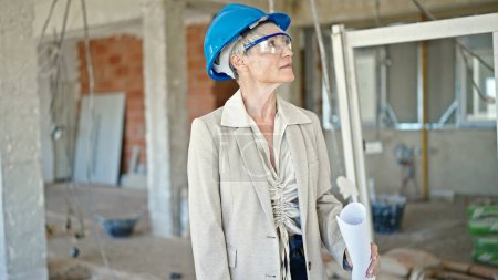 Téléchargez les photos : Moyen Age femme blonde architecte tenant projet de maison sur le chantier de construction - en image libre de droit