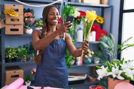 Foto de Floristería mujer afroamericana hacer foto para florecer por teléfono inteligente en la tienda de flores - Imagen libre de derechos