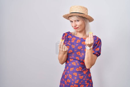 Téléchargez les photos : Jeune femme caucasienne portant des fleurs robe et chapeau d'été faisant geste d'argent avec les mains, demandant le paiement du salaire, entreprise millionnaire - en image libre de droit