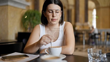 Téléchargez les photos : Jeune belle femme hispanique buvant du café assis sur la table à la cafétéria - en image libre de droit