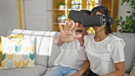 Téléchargez les photos : Homme et femme couple jouer jeu vidéo en utilisant des lunettes de réalité virtuelle à la maison - en image libre de droit