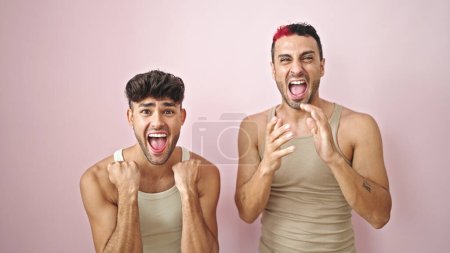 Foto de Pareja de dos hombres de pie con expresión sorpresa sobre fondo rosa aislado - Imagen libre de derechos