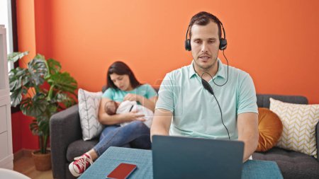 Photo for Young father with his family using laptop wearing headset at home - Royalty Free Image