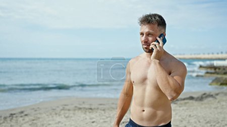 Téléchargez les photos : Jeune touriste parlant sur smartphone à la plage - en image libre de droit