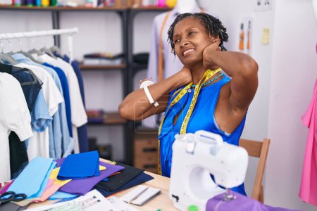 Foto de Mujer afroamericana de mediana edad estresada usando máquina de coser en atelier - Imagen libre de derechos