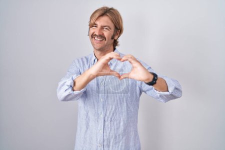 Photo for Caucasian man with mustache standing over white background smiling in love doing heart symbol shape with hands. romantic concept. - Royalty Free Image