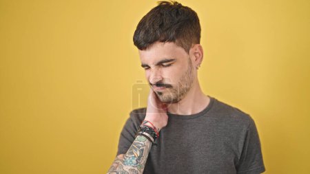 Photo for Young hispanic man suffering for cervical pain over isolated yellow background - Royalty Free Image