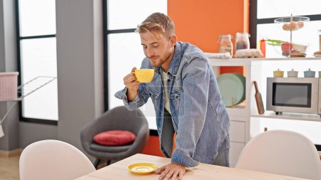 Photo for Young caucasian man drinking cup of coffee smiling at dinning room - Royalty Free Image