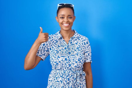 Téléchargez les photos : African american woman standing over blue background doing happy thumbs up gesture with hand. approving expression looking at the camera showing success. - en image libre de droit