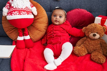 Photo for African american baby smiling confident sitting on sofa with santa claus doll at home - Royalty Free Image
