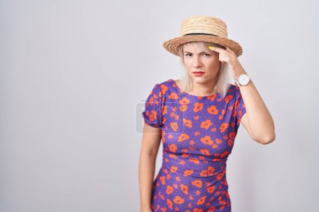Téléchargez les photos : Jeune femme caucasienne portant des fleurs robe et chapeau d'été pointant malheureux de boutons sur le front, infection laide de la tête noire. acné et problème de peau - en image libre de droit
