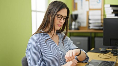 Photo for Young beautiful hispanic woman business worker looking watch at office - Royalty Free Image