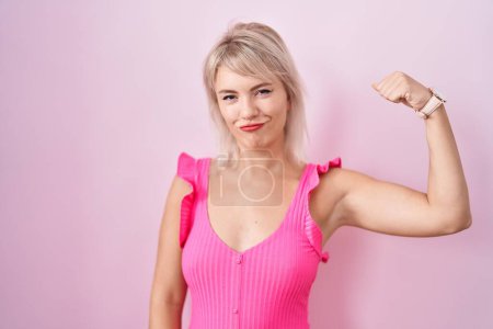 Téléchargez les photos : Jeune femme caucasienne debout sur fond rose personne forte montrant muscle du bras, confiant et fier de la puissance - en image libre de droit