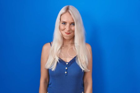 Photo for Caucasian woman standing over blue background puffing cheeks with funny face. mouth inflated with air, crazy expression. - Royalty Free Image
