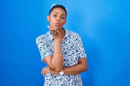 Photo for African american woman standing over blue background looking at the camera blowing a kiss with hand on air being lovely and sexy. love expression. - Royalty Free Image