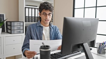 Photo for Young hispanic man business worker using laptop reading document at office - Royalty Free Image