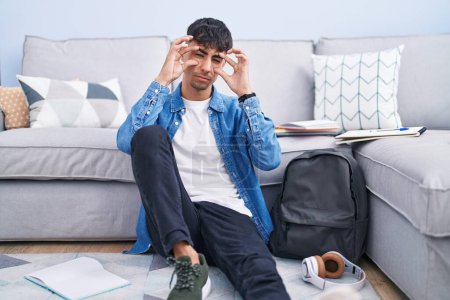 Photo for Young hispanic man sitting on the floor studying for university trying to open eyes with fingers, sleepy and tired for morning fatigue - Royalty Free Image