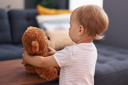 Photo for Adorable toddler playing with teddy bear standing at home - Royalty Free Image