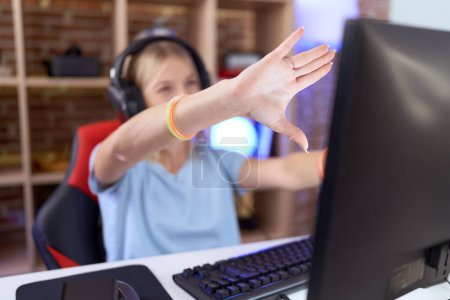 Foto de Mujer caucásica joven jugando videojuegos con auriculares haciendo marco usando las manos palmas y los dedos, perspectiva de la cámara - Imagen libre de derechos