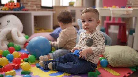 Photo for Two adorable toddlers playing with balls and car sitting on floor at kindergarten - Royalty Free Image