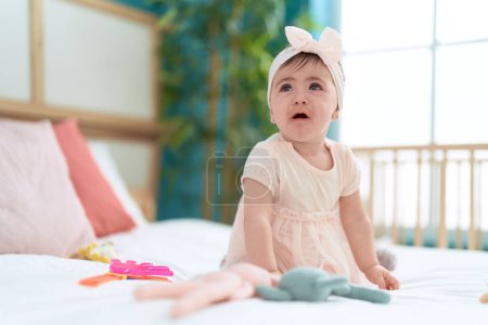 Foto de Adorable niño sentado en la cama llorando en el dormitorio - Imagen libre de derechos