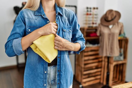Téléchargez les photos : Jeune femme blonde voleur voler sac à main au magasin de vêtements - en image libre de droit