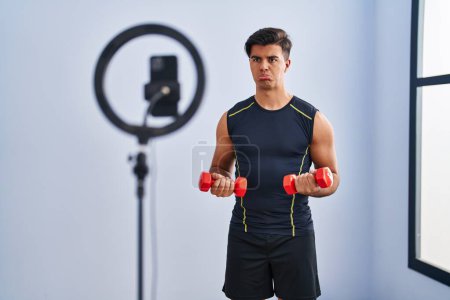 Photo for Hispanic man recording training tutorial at the gym depressed and worry for distress, crying angry and afraid. sad expression. - Royalty Free Image