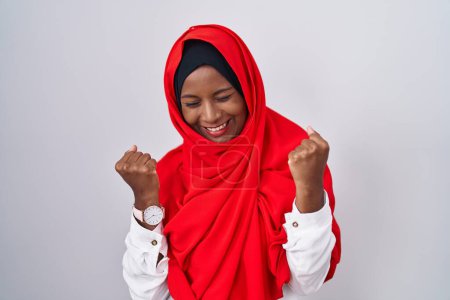 Photo for Young arab woman wearing traditional islamic hijab scarf very happy and excited doing winner gesture with arms raised, smiling and screaming for success. celebration concept. - Royalty Free Image