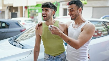 Téléchargez les photos : Deux hommes couple serrant l'autre tenant la clé de la nouvelle voiture à la rue - en image libre de droit