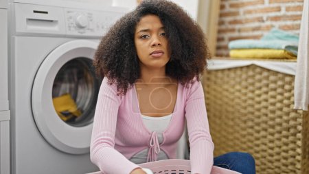 Photo for African american woman washing clothes looking upset at laundry room - Royalty Free Image