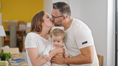 Photo for Family of mother, father and baby kissing at new home - Royalty Free Image