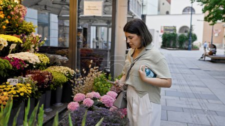 Téléchargez les photos : Jeune belle femme hispanique prenant des photos de fleurs colorées dans les rues de Vienne - en image libre de droit
