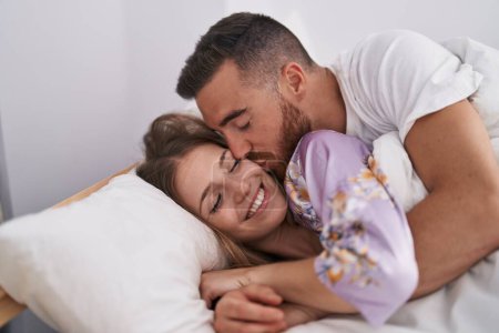 Foto de Man and woman couple lying on bed kissing at bedroom - Imagen libre de derechos